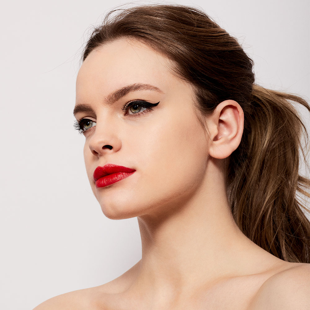 Portrait d’un mannequin au maquillage graphique avec eyeliner noir et rouge à lèvres rouge.