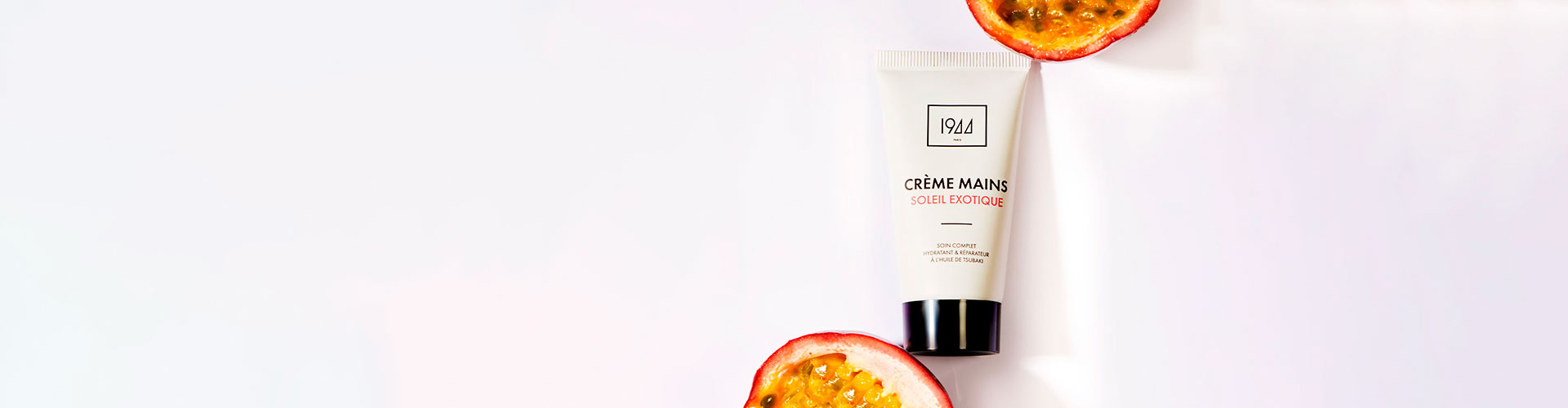 Présentation d’un tube de crème mains entouré de fruits exotiques.