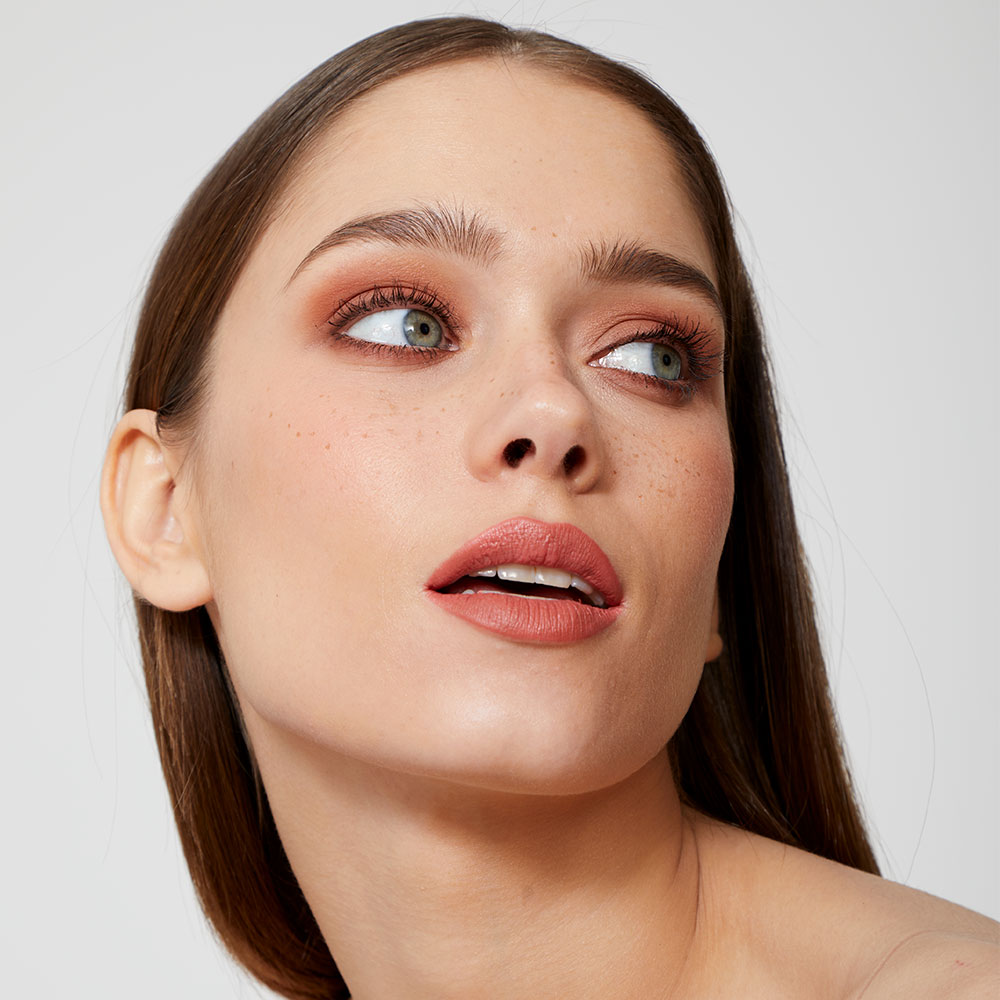 Portrait d’un mannequin au maquillage naturel et lumineux, mettant en valeur le teint et le regard.