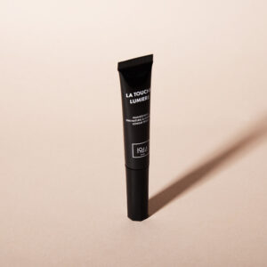 La Touche Lumière 1944 Paris highlighter in a black tube, photographed on a beige background with natural light.