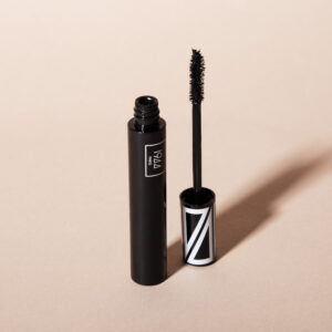 1944 Paris black mascara opened with visible brush, presented on a sleek beige background.