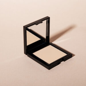1944 Paris compact powder in its black case with open mirror, photographed against a minimalist beige background.