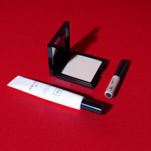 Teint Éclat Parfait complexion set, consisting of BB Crème, La Matifiante powder and L'Inoubliable concealer, laid flat on an intense red base.