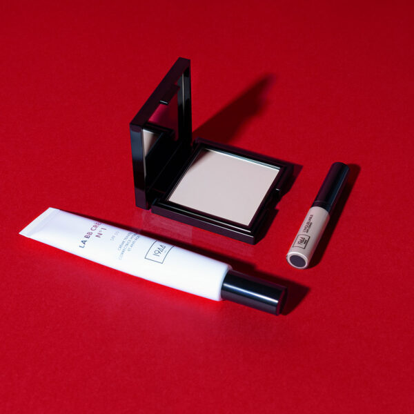 Teint Éclat Parfait complexion set, consisting of BB Crème, La Matifiante powder and L'Inoubliable concealer, laid flat on an intense red base.