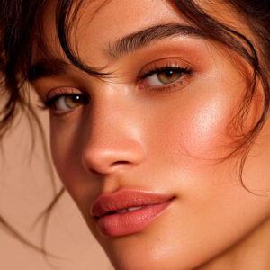 Närbildsporträtt av en kvinna med solbränd hy, naturlig makeup och lysterfull hy.