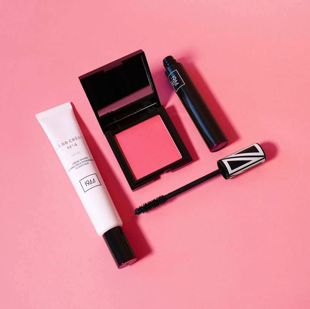 Produits coffret éclat immédiat 1944 Paris BB crème, mascara et blush disposés sur fond rose