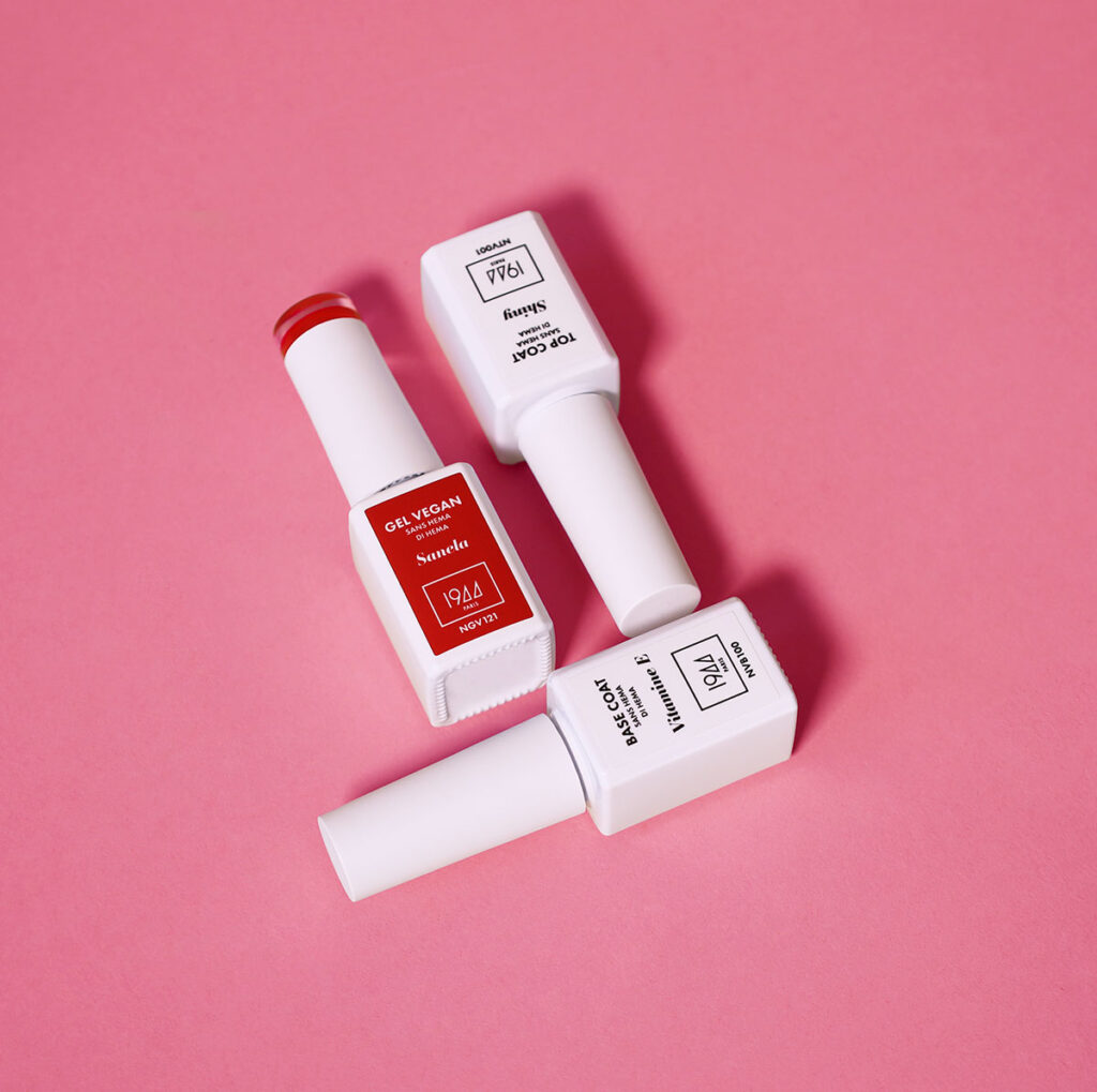 Produits du coffret manucure parfaite 1944 Paris base coat gel vegan et top coat disposés sur fond rose