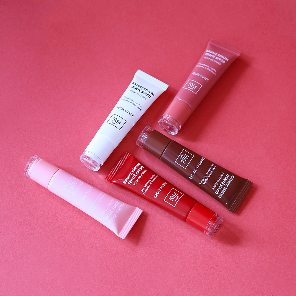 Flat lay des Baumes Sérum Teinté SPF50 1944 Paris sur fond rose avec packaging glossy et teintes éclatantes.