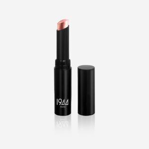 Stick Glow 1944 Paris en tono melocotón rosado, con el tapón negro junto a él, sobre un fondo gris claro