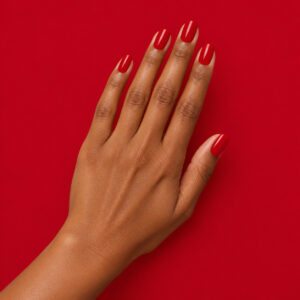 Hands with a manicure using Karine vegan nail varnish, in a deep red shade, against a background matching the shade – 1944 Paris