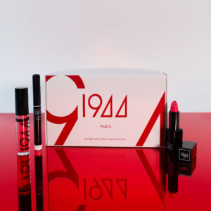 “Le Rouge Désir 1944 Paris”礼盒：红白相间的礼盒，周围摆放着“Gloss Brillant Ultra”唇彩、“Base Lèvres Universelle”唇部打底霜和“Rouge à Lèvres Mat Icône”哑光唇膏，置于闪亮的红色底座上