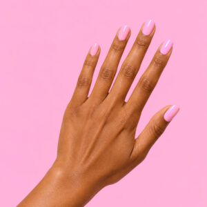 A hand with olive-toned skin, wearing Ellen’s candy pink vegan semi-permanent gel, against a candy pink background
