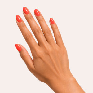 Main à la peau mate portant le gel semi-permanent vegan Coraline corail orangé, sur fond rose pâle