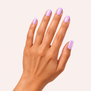 Mano de piel morena con el esmalte semipermanente vegano «Agnès lilas», sobre un fondo beige rosado