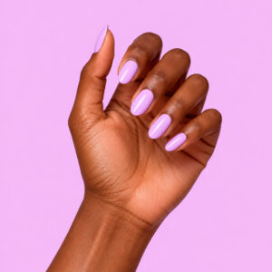 Mano de piel oscura con el esmalte semipermanente vegano «Agnès lilas», sobre un fondo lila