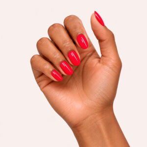 Main à la peau mate portant le gel semi-permanent vegan Adrienne rouge, sur fond rose pâle